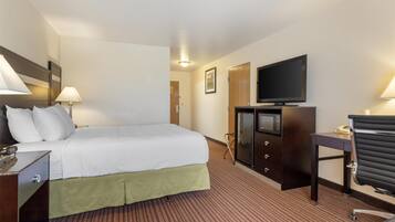 A hotel room with a bed, desk, television, and a microwave.