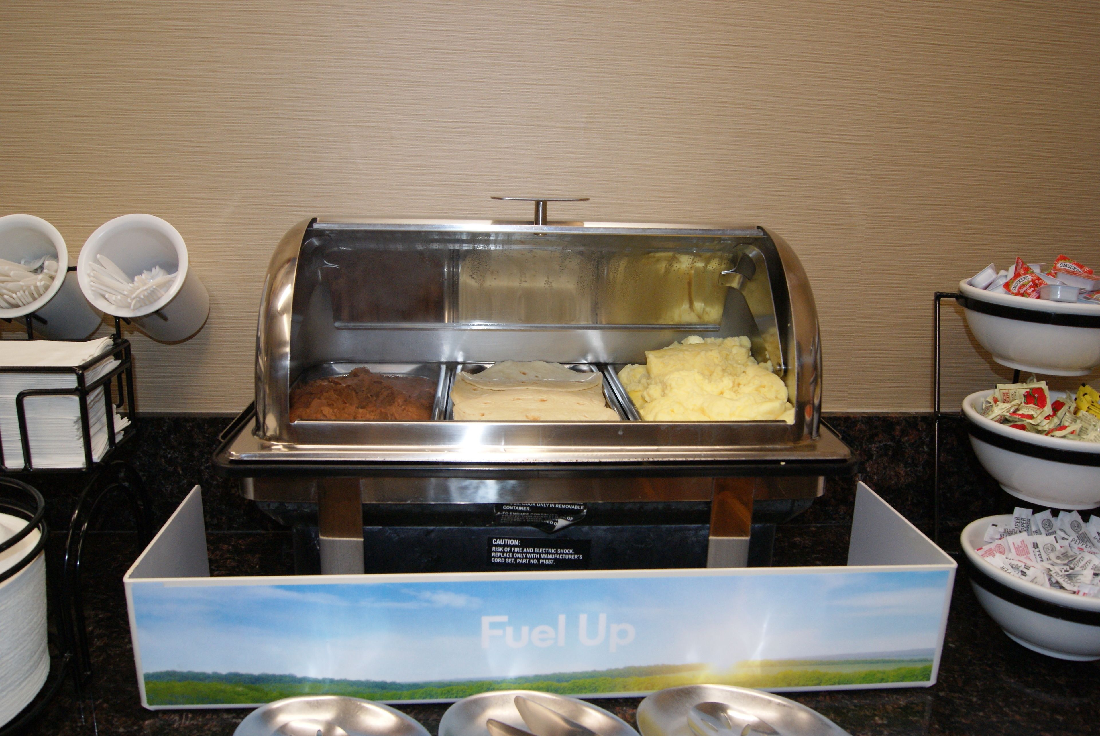 A buffet area with various food items and utensils.