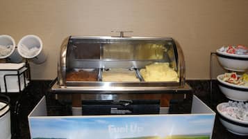 A buffet area with various food items and utensils.