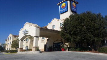 Un hotel Comfort Inn & Suites con un letrero llamativo, entrada cubierta y estacionamiento.