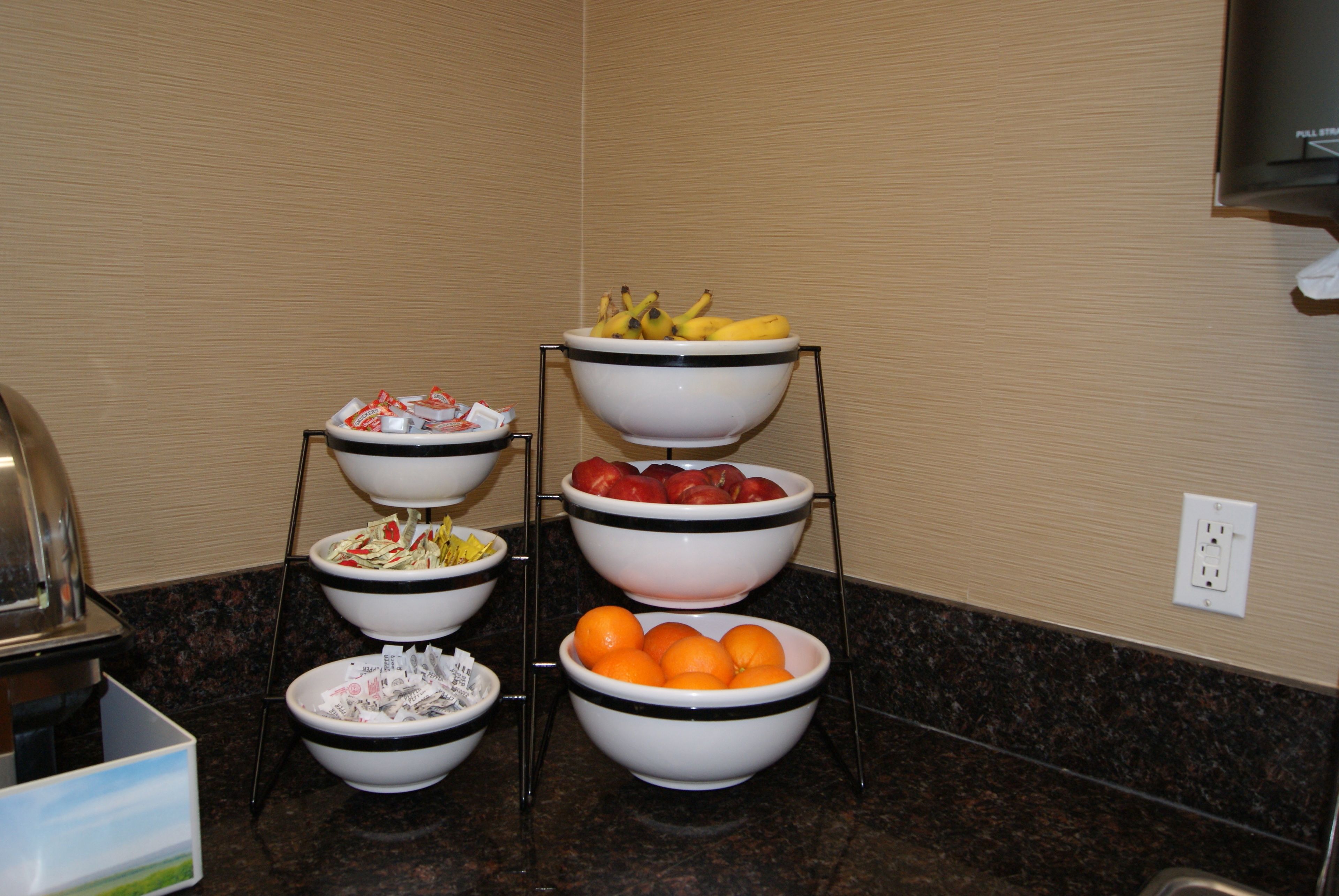 A buffet setup with multiple bowls of fruits and vegetables on a stand.