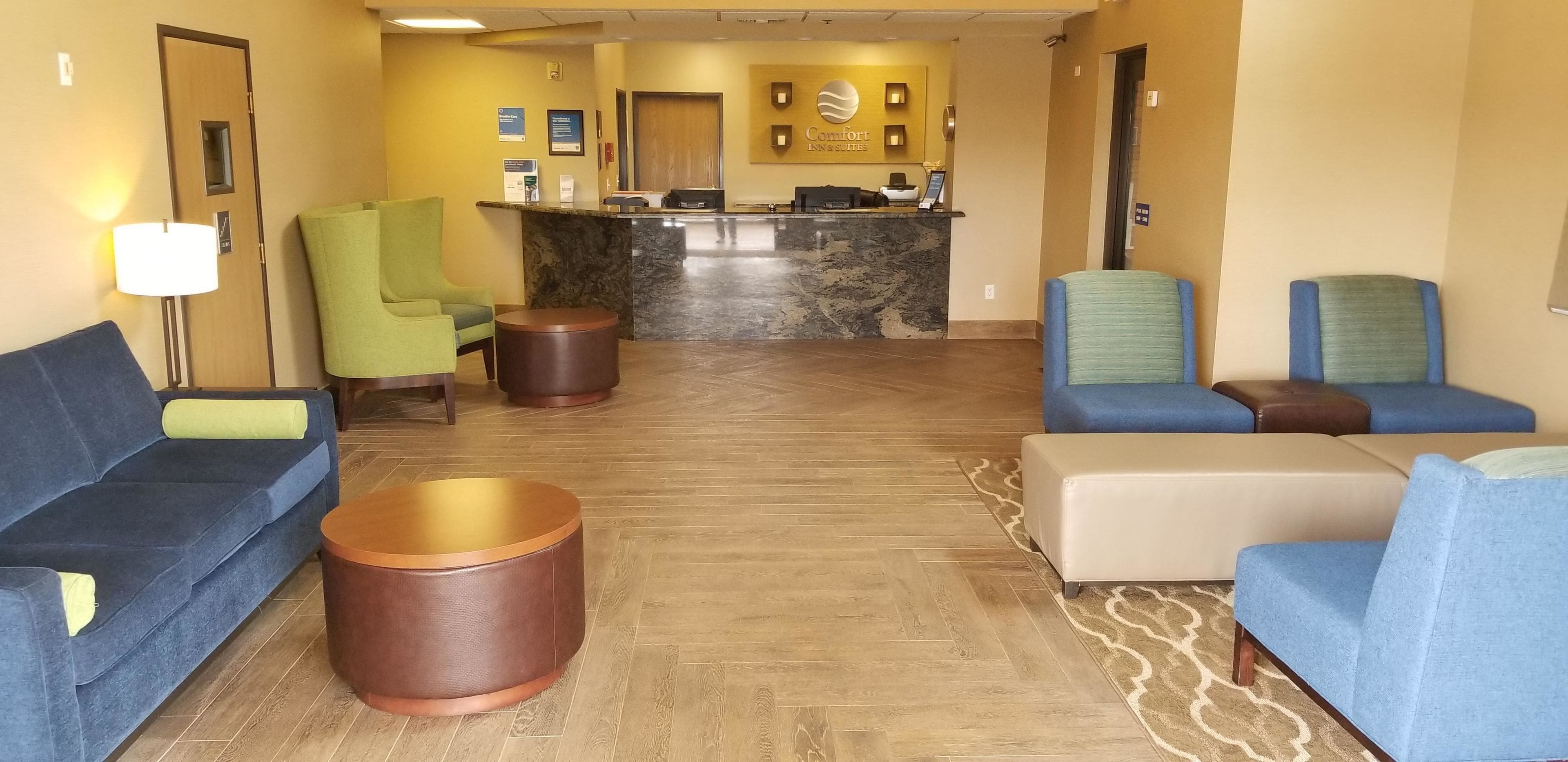 A hotel lobby with a reception desk, seating area, and a wooden floor.