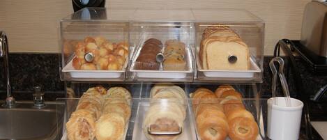Mostrador de panadería con diferentes productos horneados en recipientes transparentes.