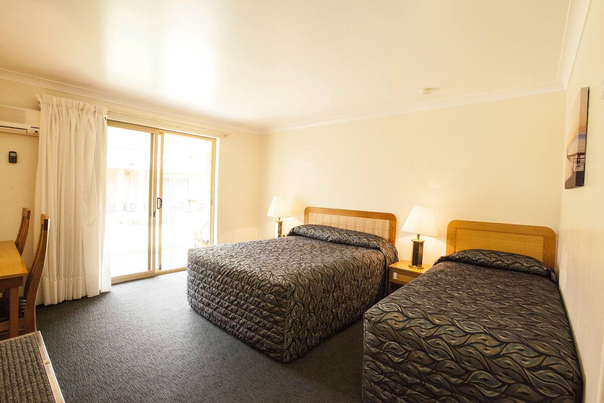 Une chambre d’hôtel avec deux lits, un bureau et une chaise.