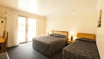 A hotel room with two beds, a desk, and a chair.