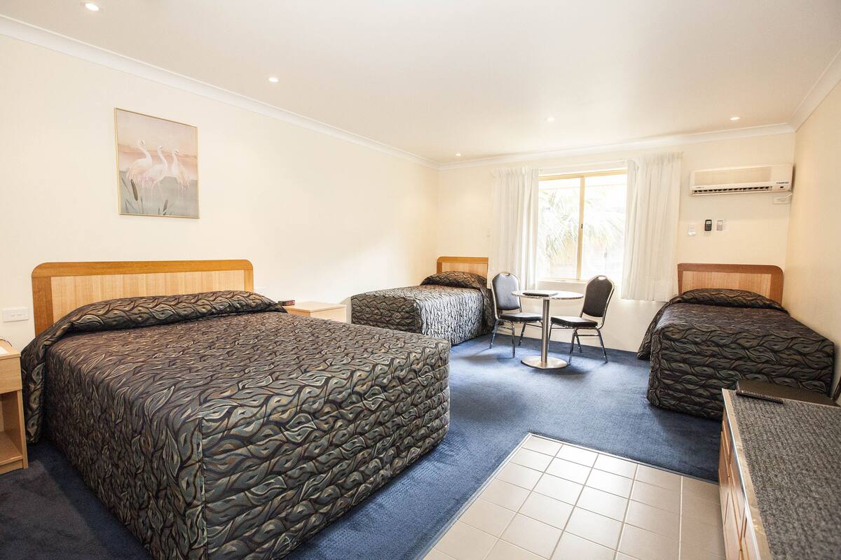 Une chambre d’hôtel avec deux lits, un bureau et une chaise.