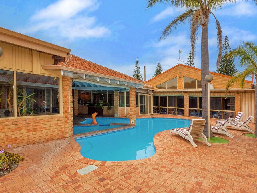 A pool area with lounge chairs and a covered patio.