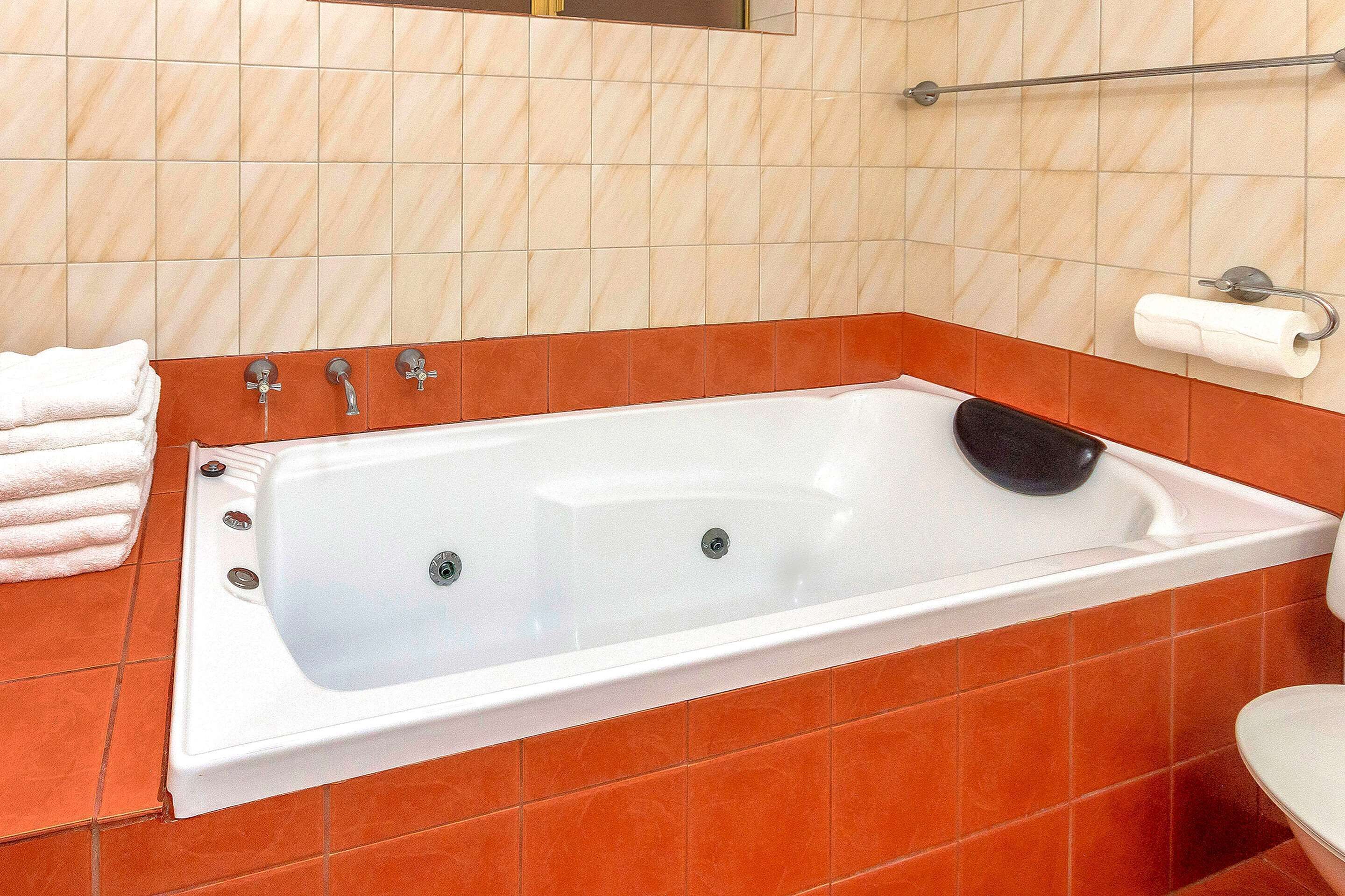A bathroom with a bathtub, a toilet, and a towel rack.