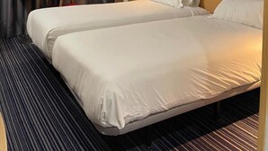 A hotel room with two beds, a small table, a chair, and a nightstand with a phone. - Holiday Inn Express Madrid-San Sebastian de los Reyes by IHG (San Sebastian de los Reyes)