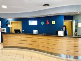 Un mostrador de recepción de hotel con una pared azul, un reloj y un cartel que dice 'Hampton Inn Express'.