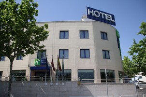 Un edificio de hotel con un letrero grande que dice 'HOTEL', múltiples ventanas y un letrero de Holiday Inn Express.