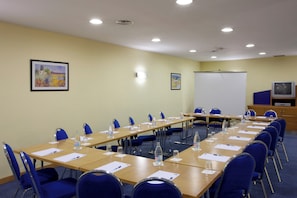 A conference room with long tables, chairs, water bottles, and a whiteboard.