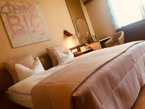 A hotel room with a bed, pillows, a bedside table, a mirror, and a motivational poster on the wall. - Minotel Casino (Sierre)