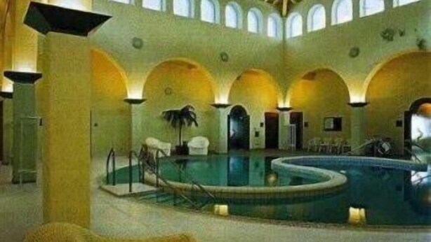 Uma grande piscina coberta com várias arcadas e teto alto.