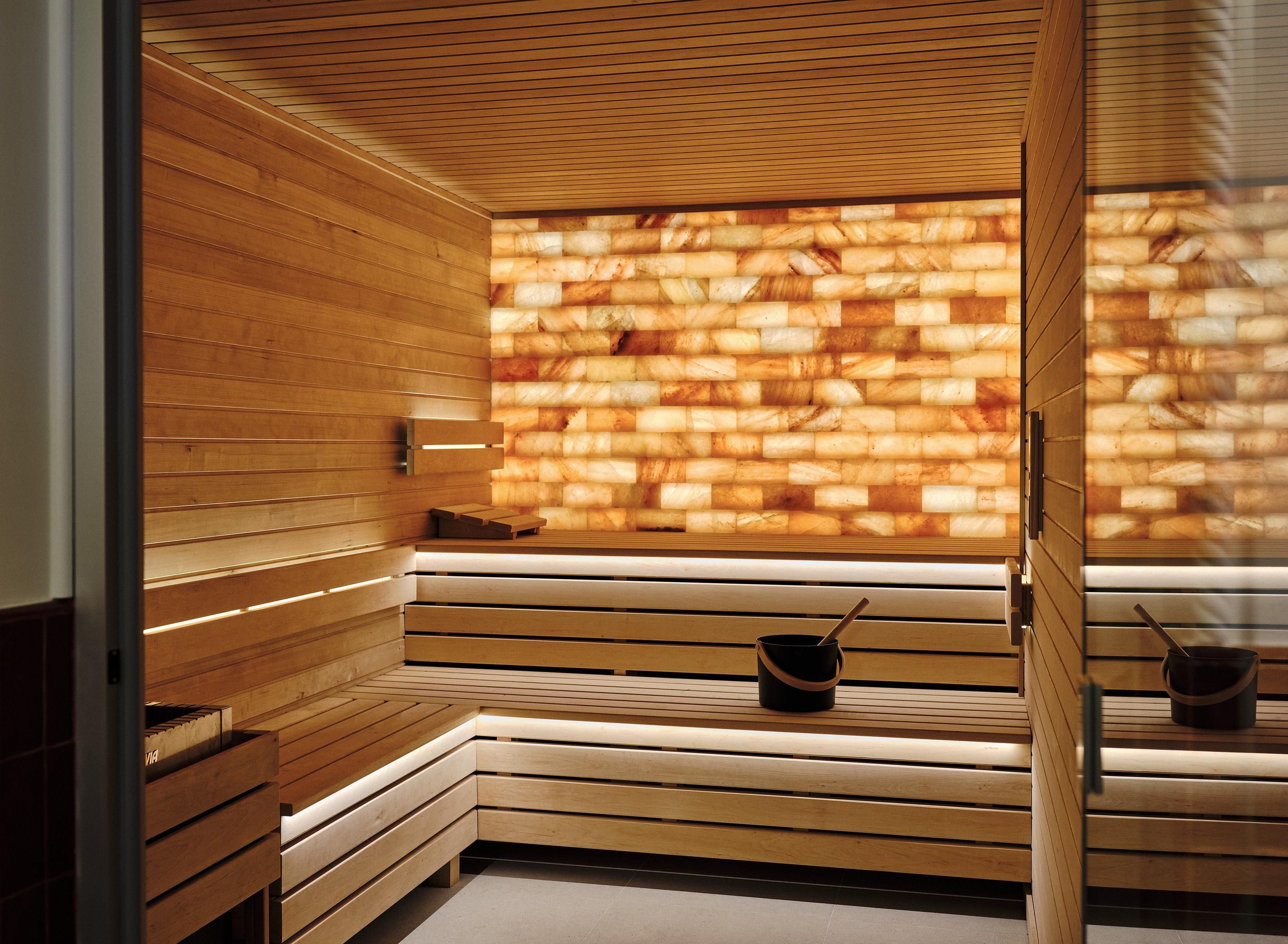 A sauna with wooden benches and a stone wall.