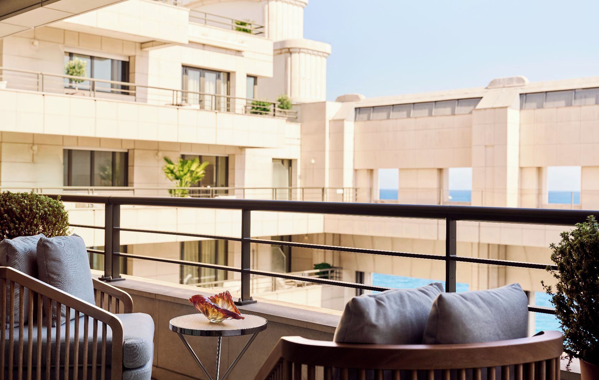Un balcon avec un canapé, une petite table ronde et un objet décoratif en verre.