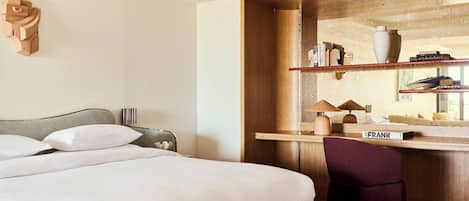A hotel room with a bed, a desk, a chair, and a bookshelf.