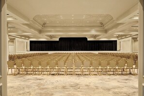 A conference room with rows of chairs, a stage with a black backdrop, and a patterned carpet. - Hôtel Palais de la Méditerranée In The Unbound Collection By Hyatt (Nice)