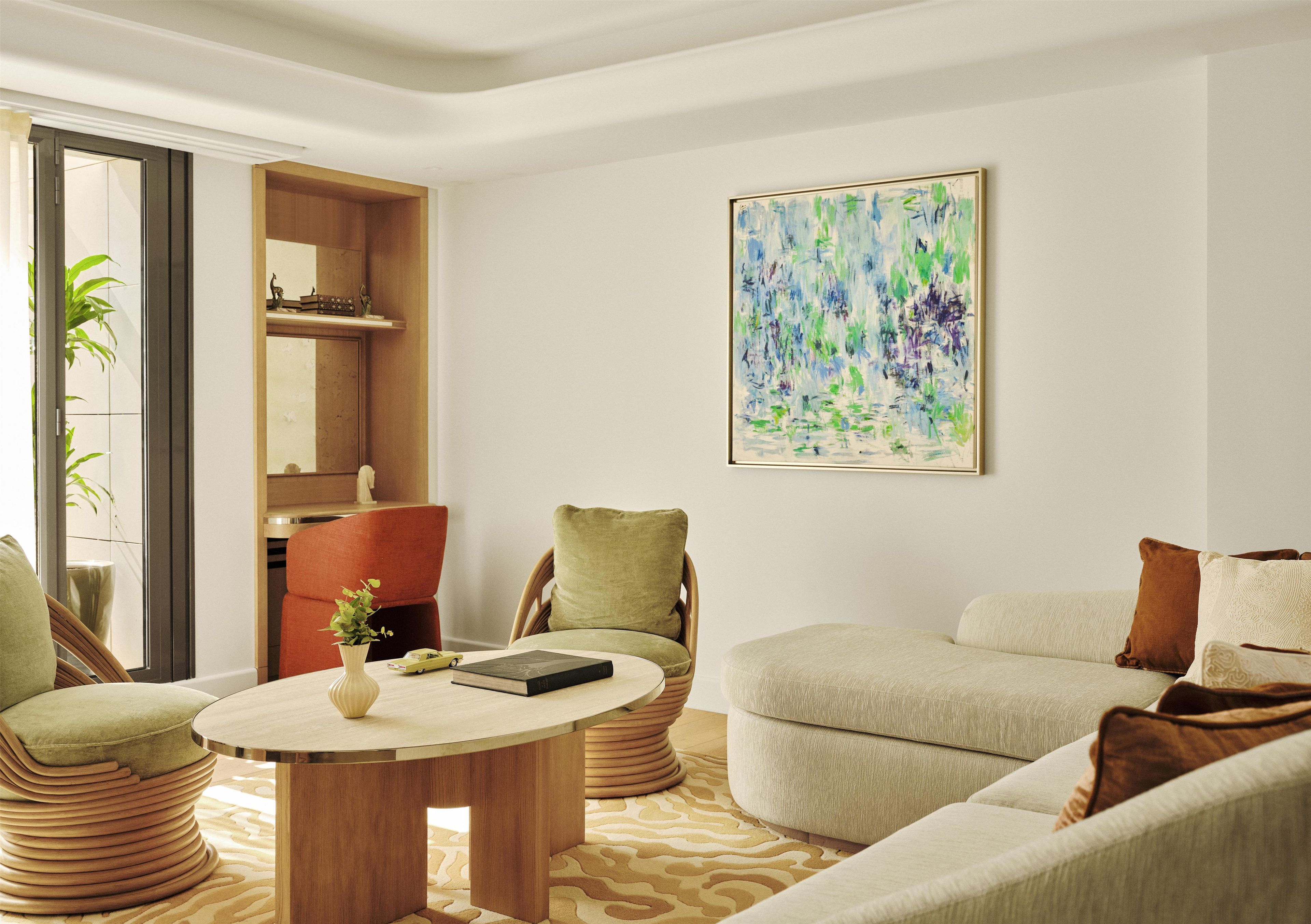 A modern living room with a round coffee table, cushioned seating, and a large abstract painting on the wall.