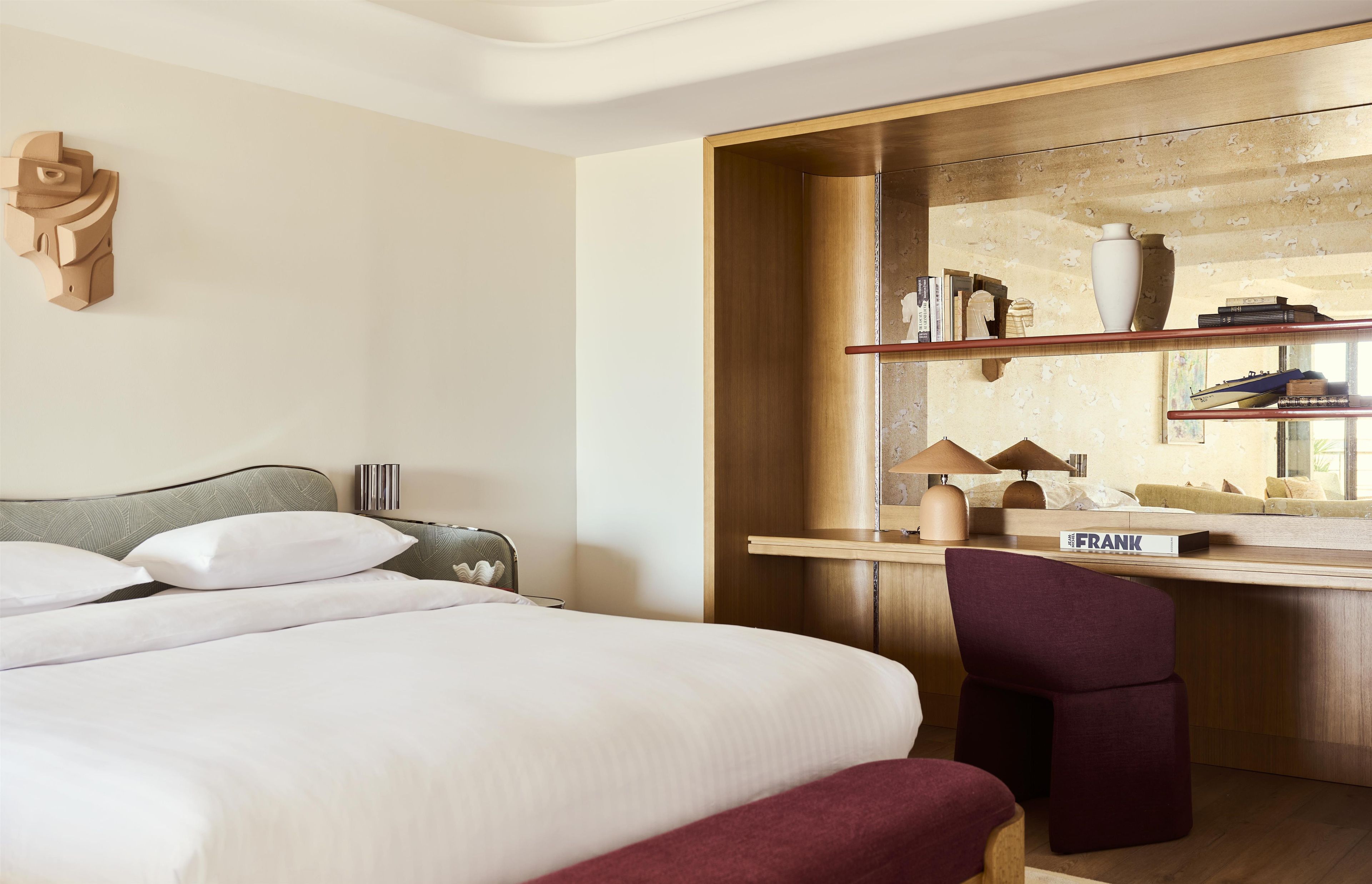 Una habitación de hotel con una cama, un escritorio, una silla y un espejo.
