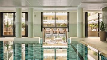 En swimmingpool med utsikt över utomhusområdet med sittplatser och en vägg av glas.