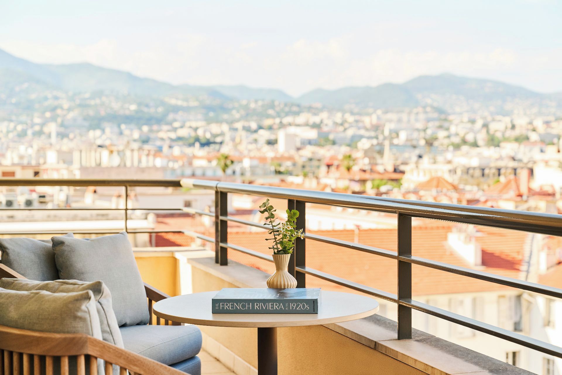 Un balcon avec une table ronde, une chaise et un livre intitulé « La Côte d’Azur dans les années 1920 ».