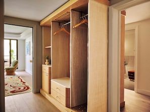 A walk-in closet with wooden shelving, a hanging rod, and a bench. - Hôtel Palais de la Méditerranée In The Unbound Collection By Hyatt (Nice)