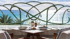 A dining table with bowls, glasses, and a bottle, set against a scenic ocean view. - Hôtel Palais de la Méditerranée In The Unbound Collection By Hyatt (Nice)
