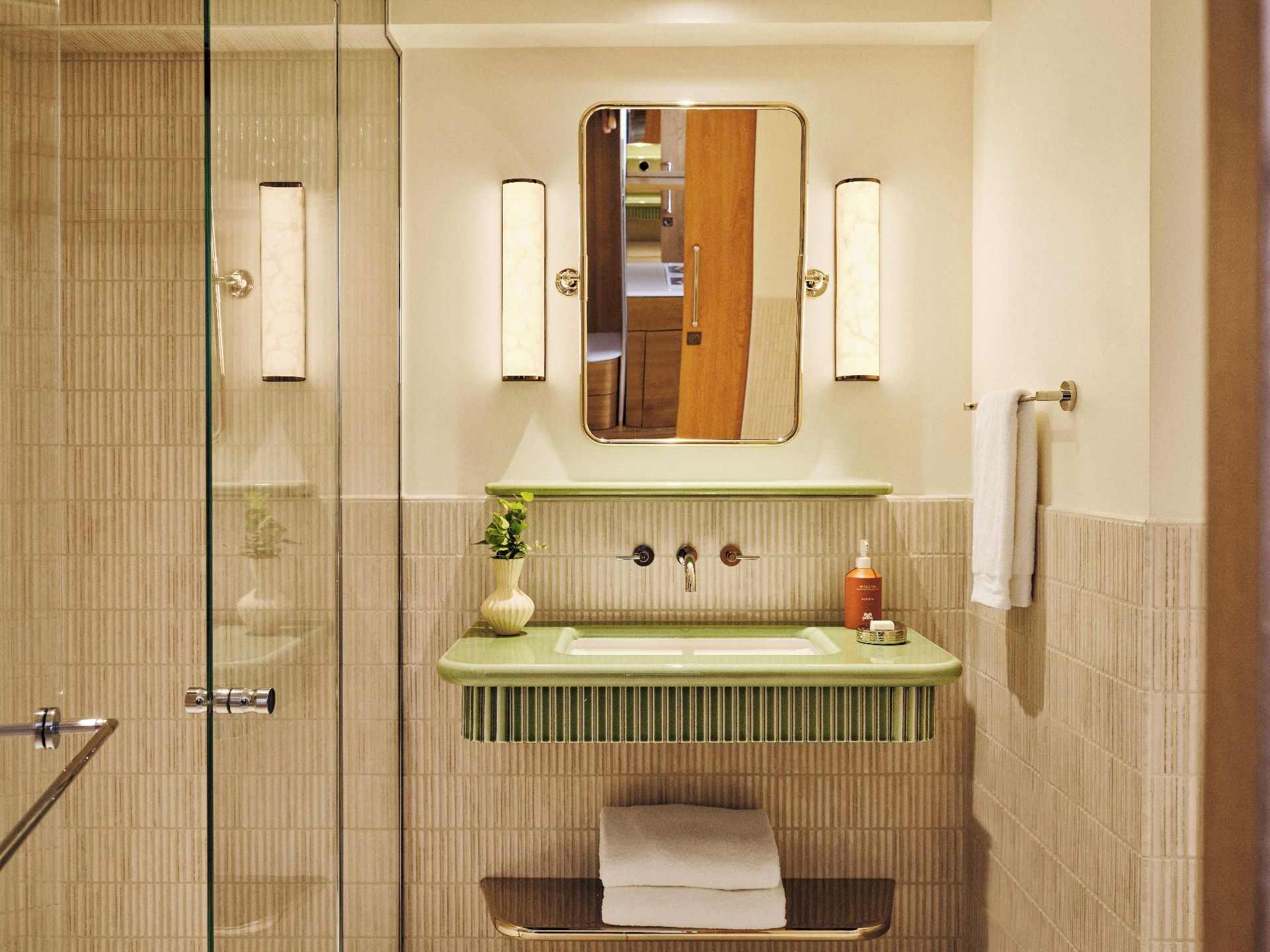 Une salle de bain avec une douche à parois de verre, un meuble-lavabo vert avec un miroir et un porte-serviettes.