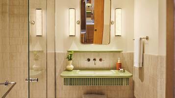 A bathroom with a glass shower enclosure, a green vanity with a mirror, and a towel rack.