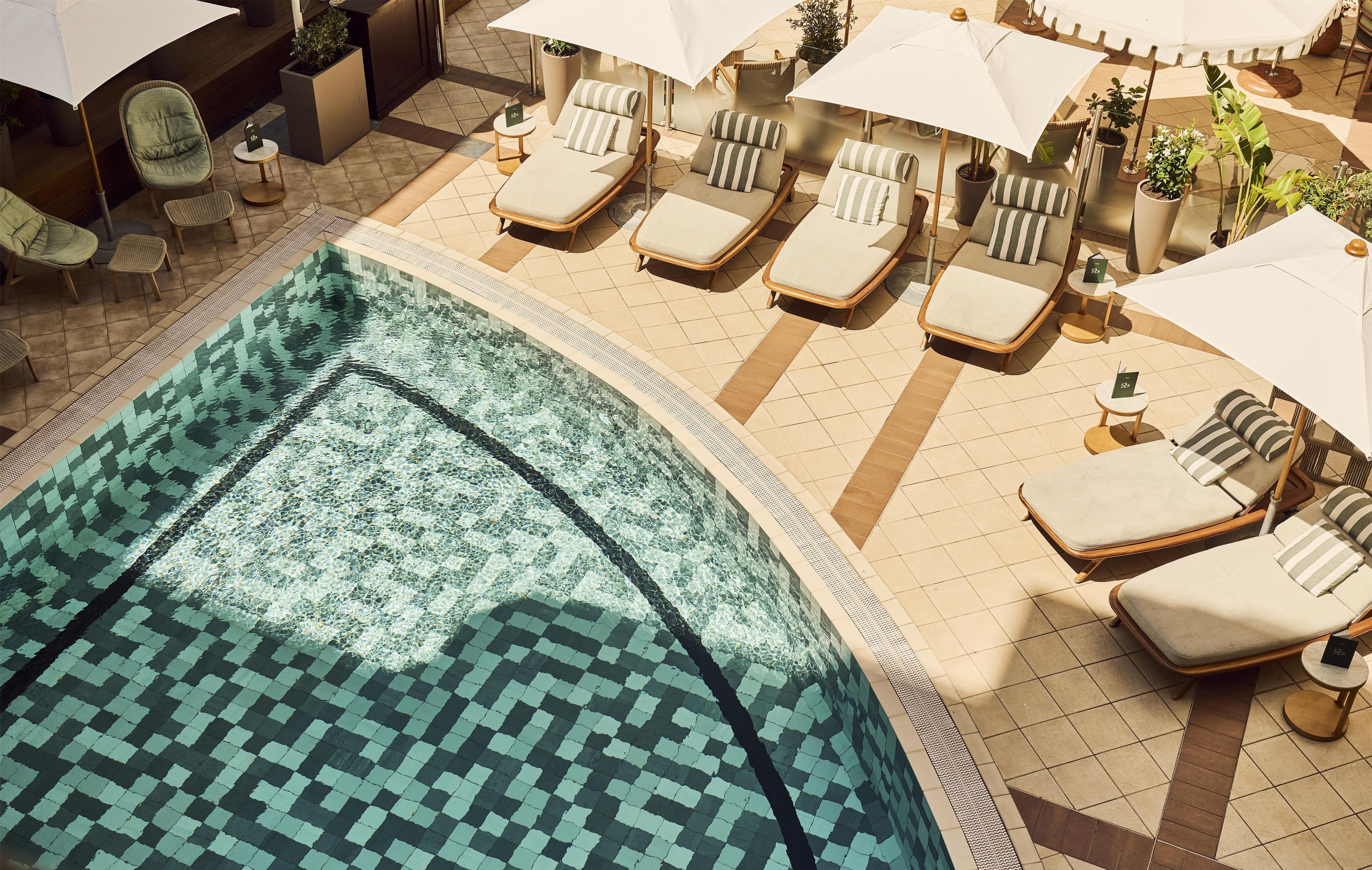 Un área de piscina con sillas de descanso y sombrillas.