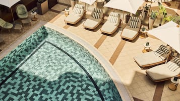 Un área de piscina con sillas de descanso y sombrillas.