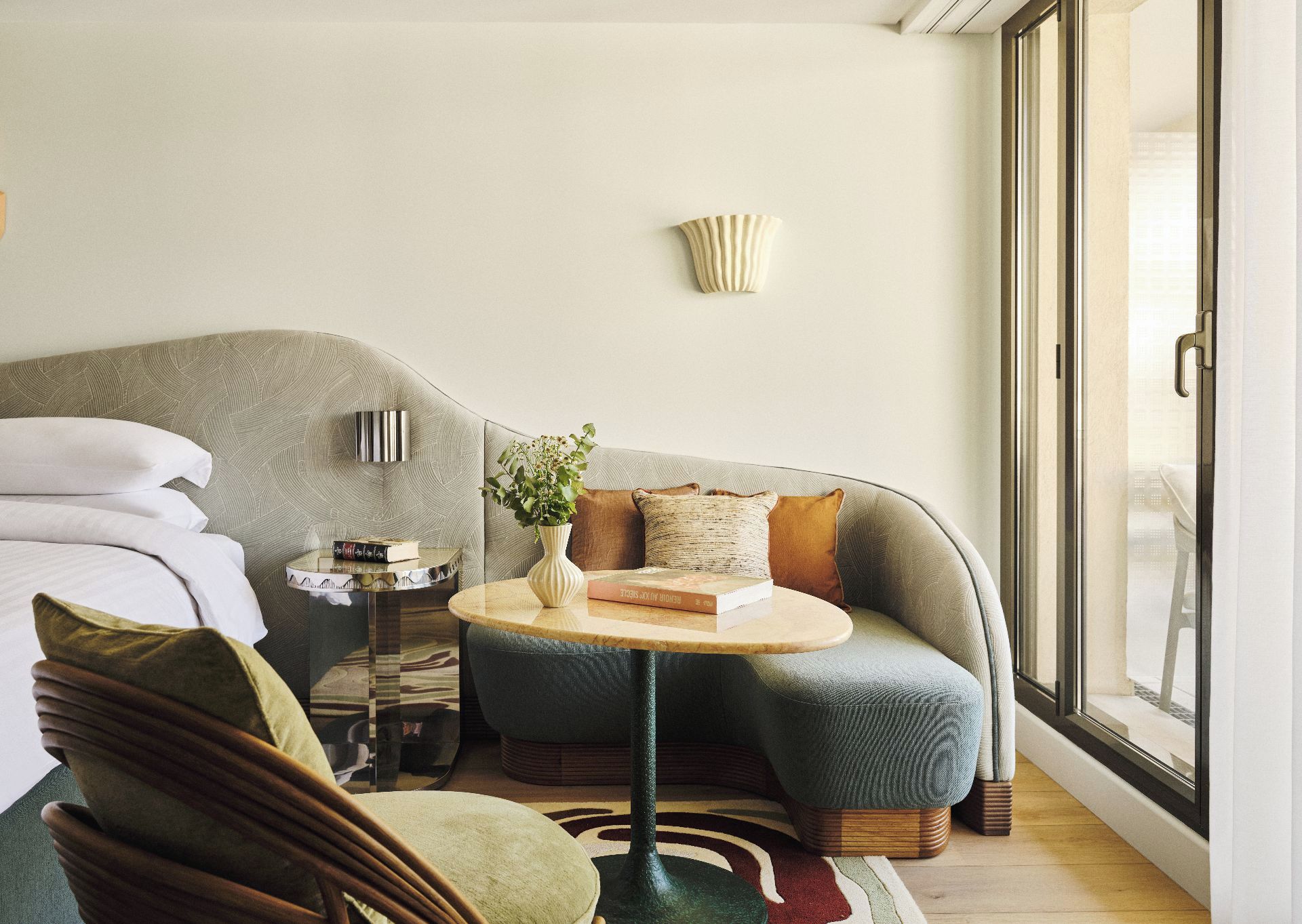 Una sala de estar moderna con un sofá, una mesita redonda, una silla y un ventanal grande.