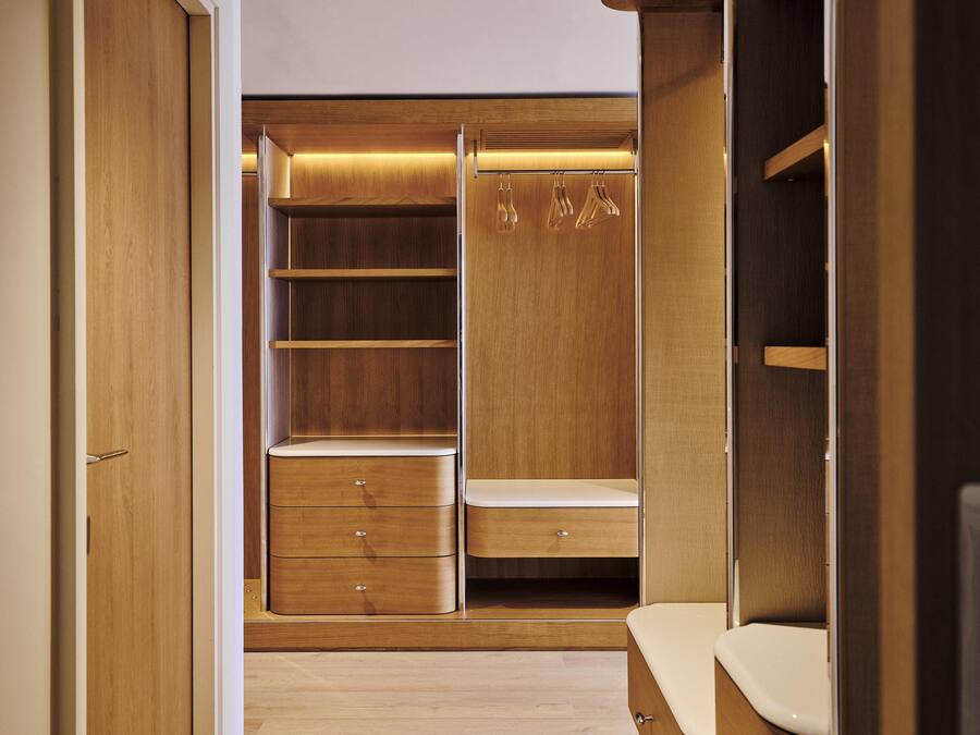 Un vestidor con estantes de madera, cajones y espacio para colgar ropa.