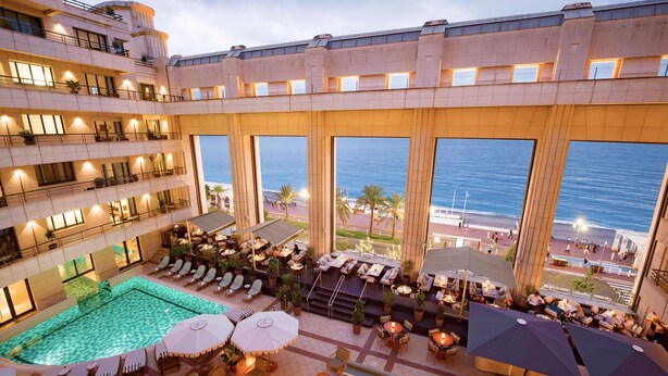 A hotel rooftop with a swimming pool, outdoor seating, and large windows overlooking the ocean. - Hôtel Palais de la Méditerranée In The Unbound Collection By Hyatt (Nice)