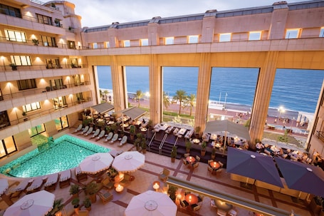 A hotel rooftop with a swimming pool, outdoor seating, and large windows overlooking the ocean.. Hôtel Palais de la Méditerranée In The Unbound Collection By Hyatt