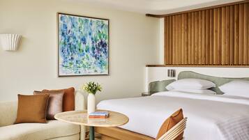 A hotel room with a bed, a sofa, a round table, and a painting on the wall.