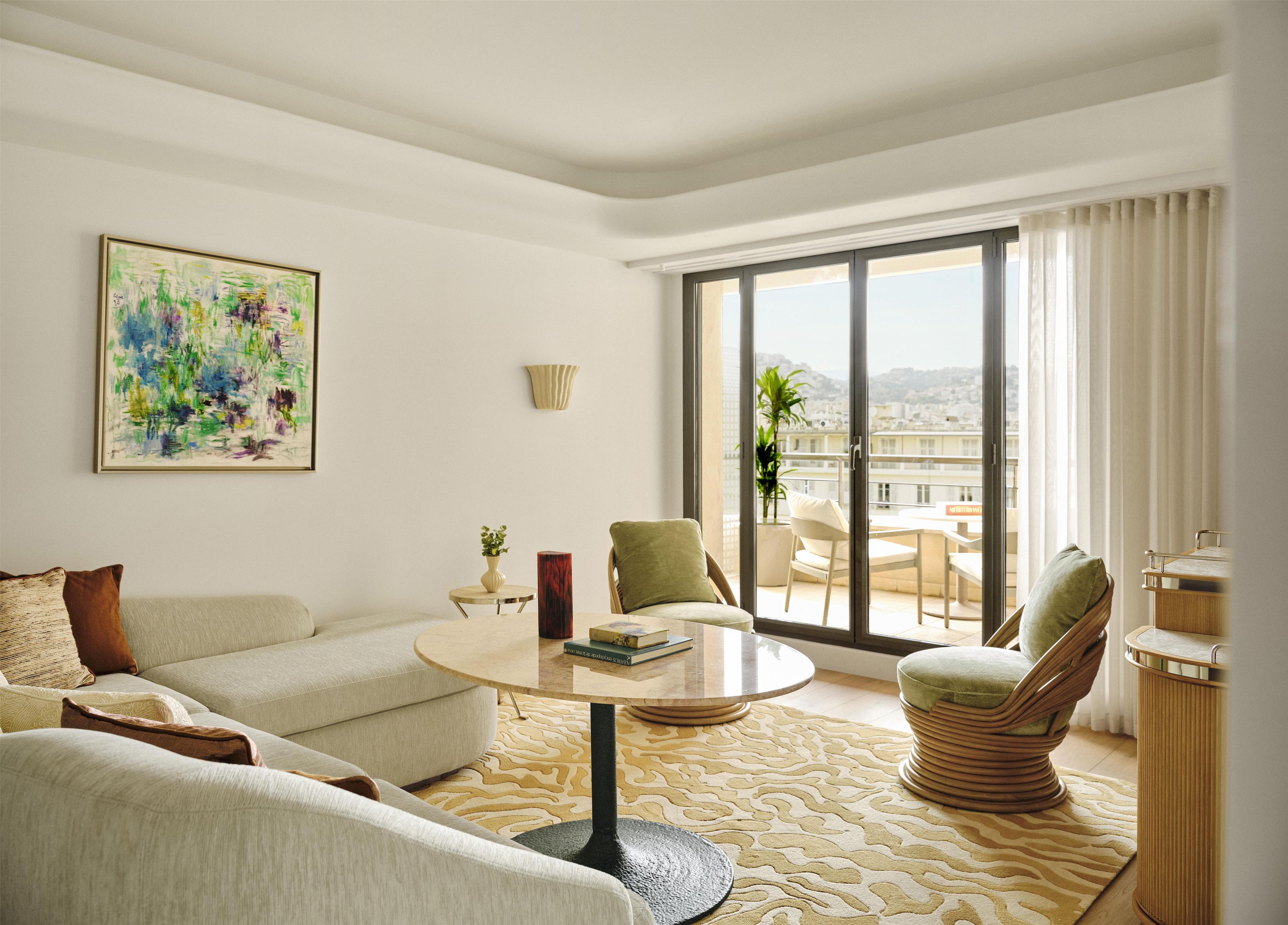 Sala de estar moderna com sofá, mesa de centro redonda e vista para uma varanda com mobiliário de exterior.