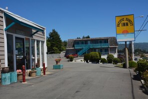 A Pacific Sunset Inn with a two-story building, a visible office on the ground floor, and a staircase leading to the upper level.