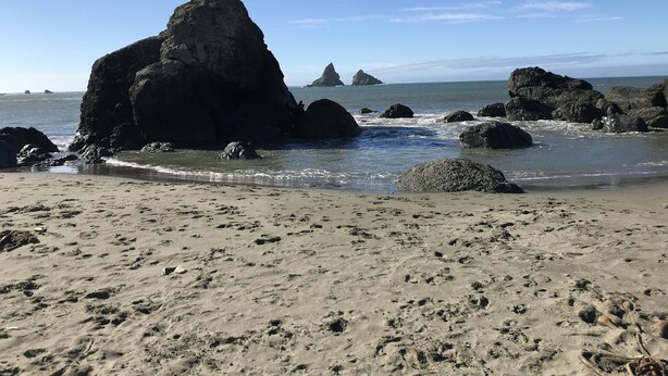 Une plage avec de gros rochers et un ciel dégagé.