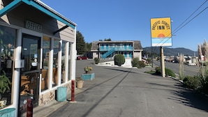 Un bâtiment avec une enseigne indiquant « Pacific Sunset Inn », un petit bureau et une voiture rouge garée devant.