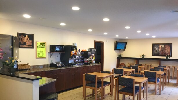 Een restaurant met een balie, een zithoek en een aan de muur bevestigde televisie.