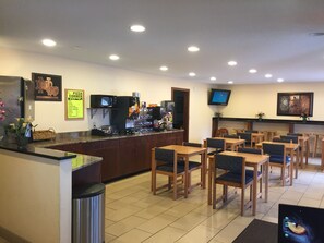 A restaurant with a counter, seating area, and a TV mounted on the wall. - StayInn - Grand Forks (Grand Forks)