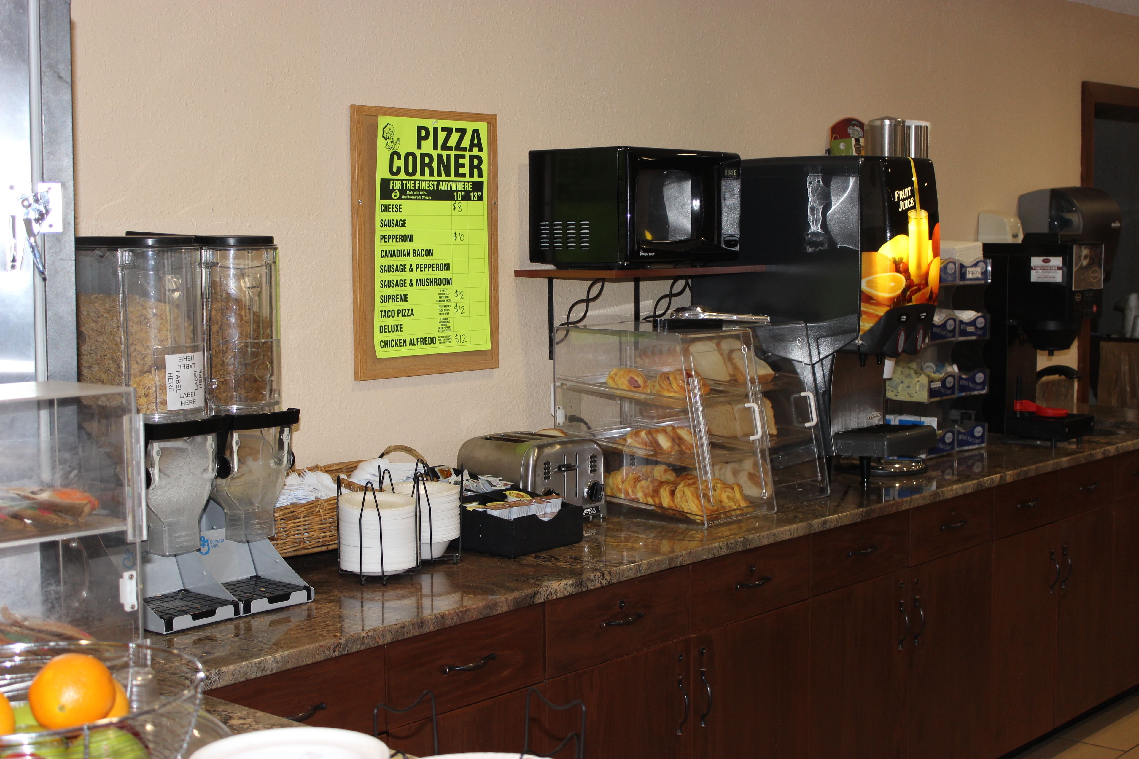 A kitchen counter with a pizza menu, a microwave, a coffee machine, and various food items.