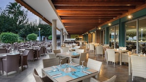 An outdoor dining area with wicker furniture and tables set for guests.