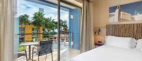 A hotel room with a balcony, a bed, a table, and chairs.
