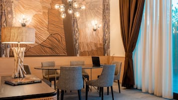 A modern dining area with a round table, grey upholstered chairs, a lamp, and a wall with a wood-like pattern.