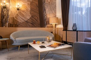 Een moderne woonkamer met een grijze bank, een witte salontafel en een decoratieve wand met abstracte patronen.