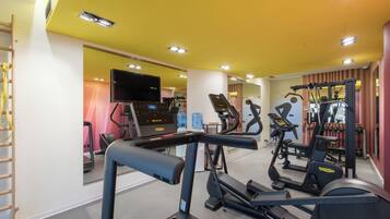 A gym with treadmills, elliptical machines, and a weight bench.