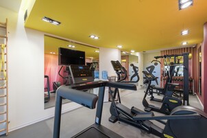 A gym with treadmills, elliptical machines, and a weight bench.